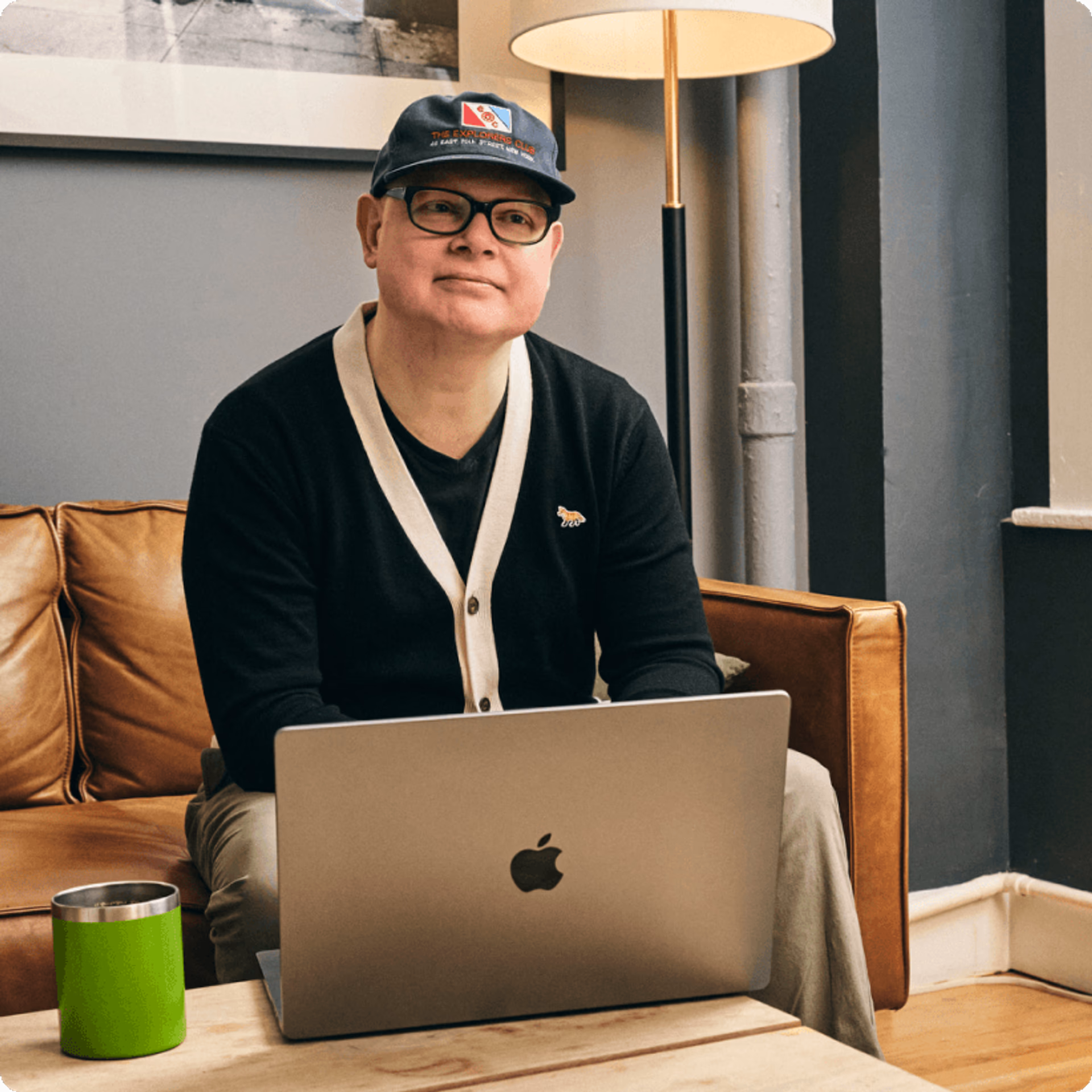 Person sitting on a couch with a laptop in a cozy indoor setting.