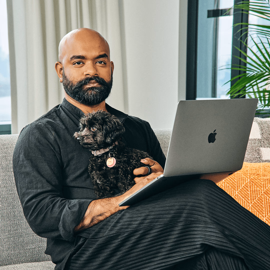 A man working from home with a laptop and a pet.