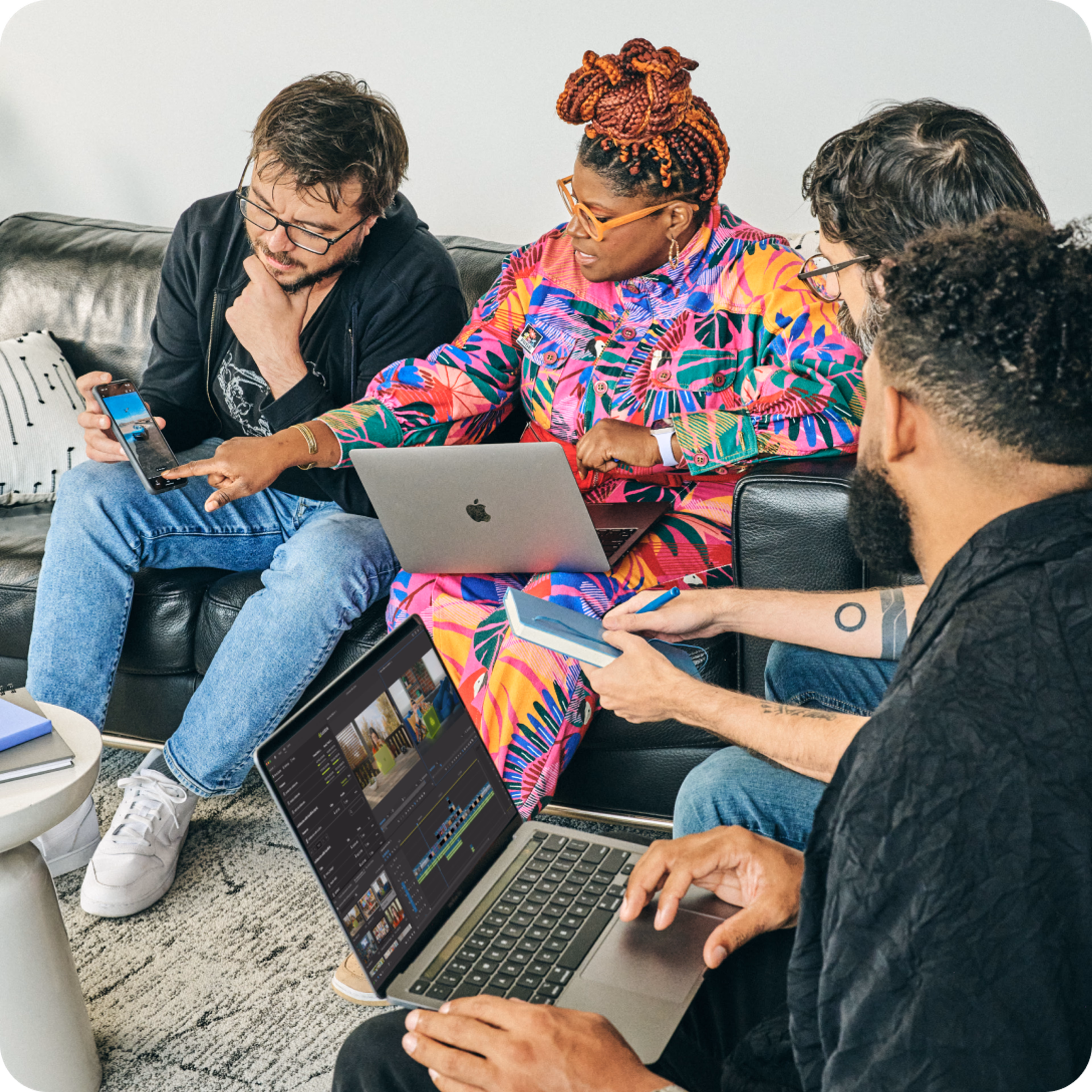 Creative professionals discussing a project and working on a laptop.